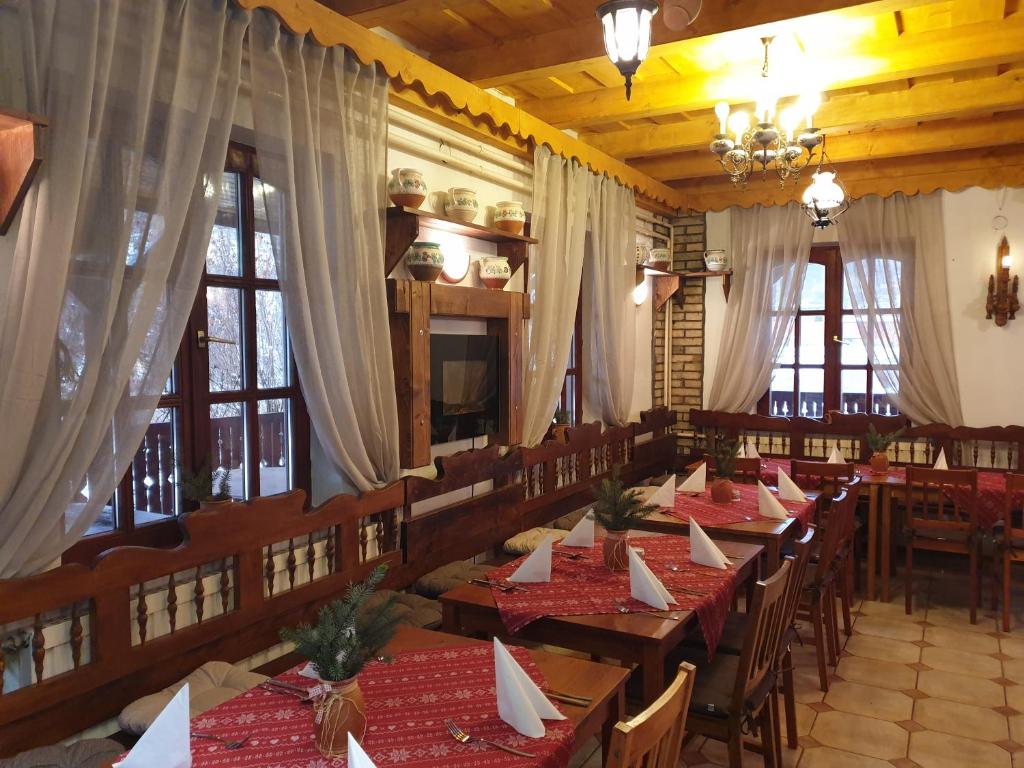 restauracja z drewnianymi stołami, krzesłami i oknami w obiekcie Fakanalas Fogadó w mieście Pásztó
