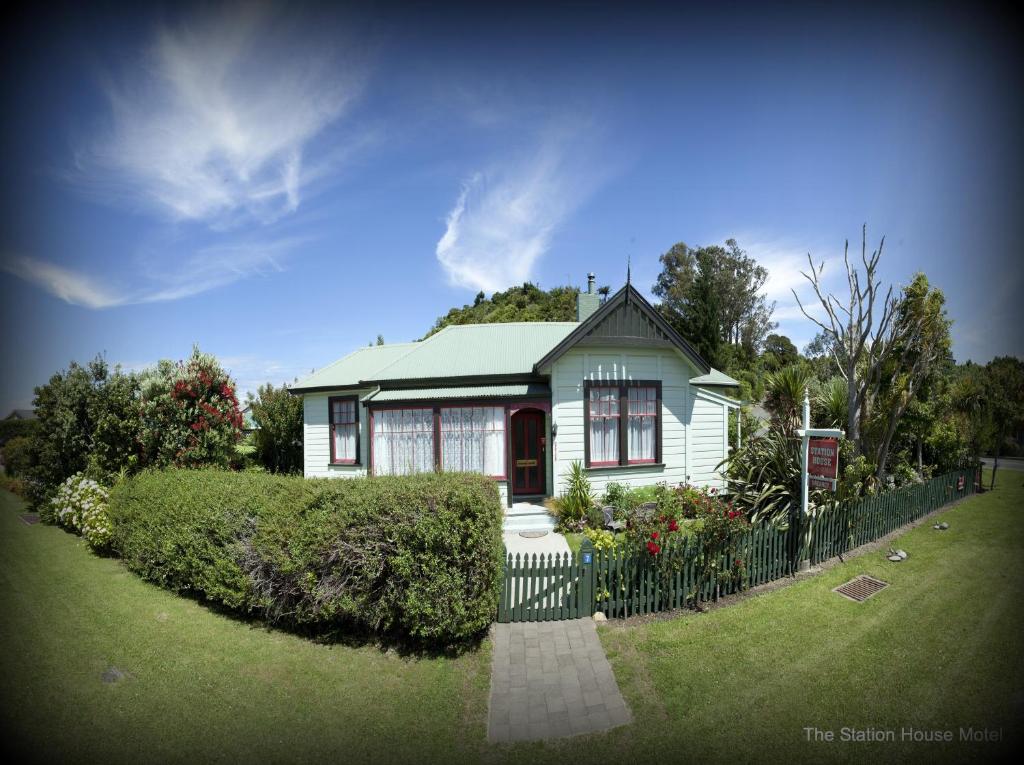 ein kleines weißes Haus mit einem Zaun im Hof in der Unterkunft The Station House Motel in Collingwood