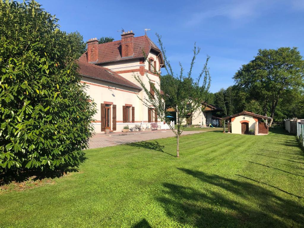 ein großes Haus mit einem Hof mit einem Baum in der Unterkunft Ancienne Gare du Val des Bois in Warmeriville