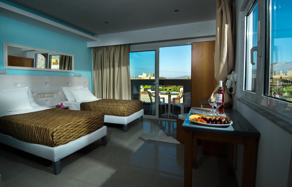 een hotelkamer met twee bedden en een tafel met een bord eten bij Kastro Beach Apartments in Malia