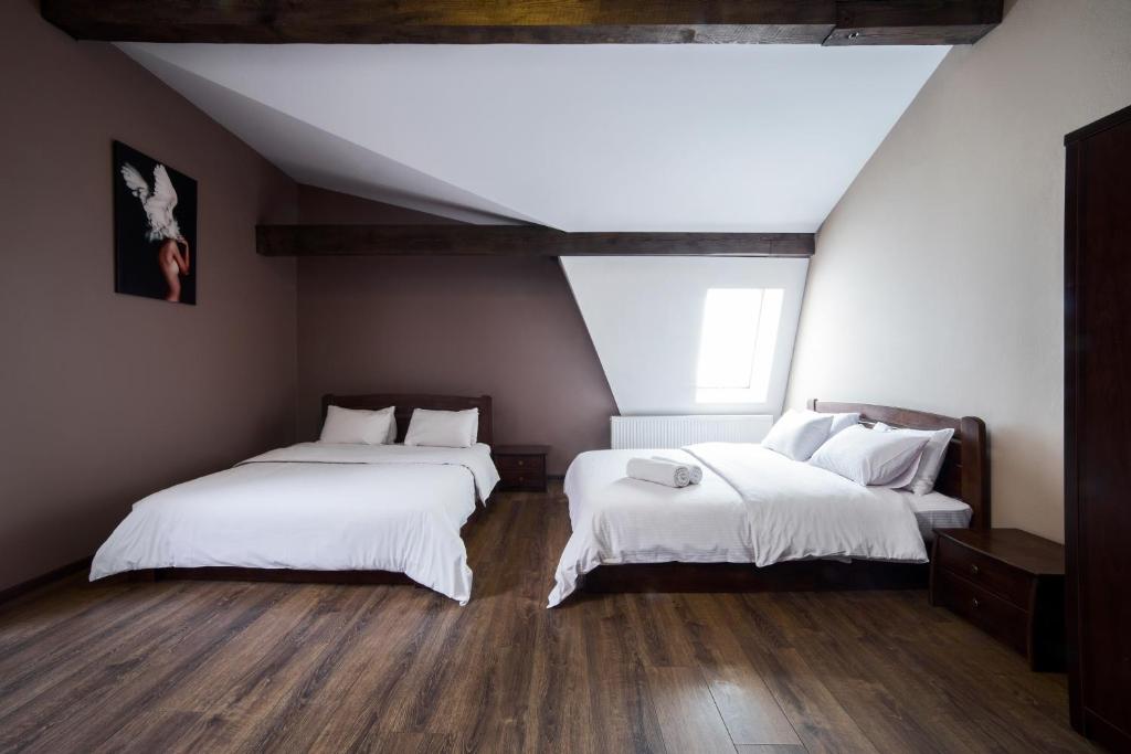 twee bedden in een kamer met witte lakens en houten vloeren bij Апартаменти в центрі на площі Митній in Lviv