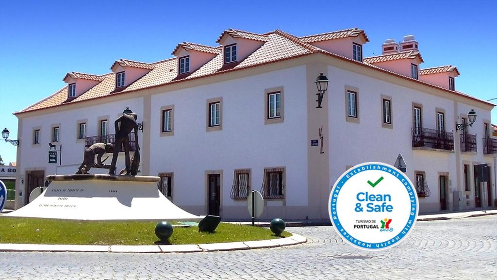 a statue in front of a building with a sign in front at Casa do Largo - Golegã - Turismo de Habitação in Golegã