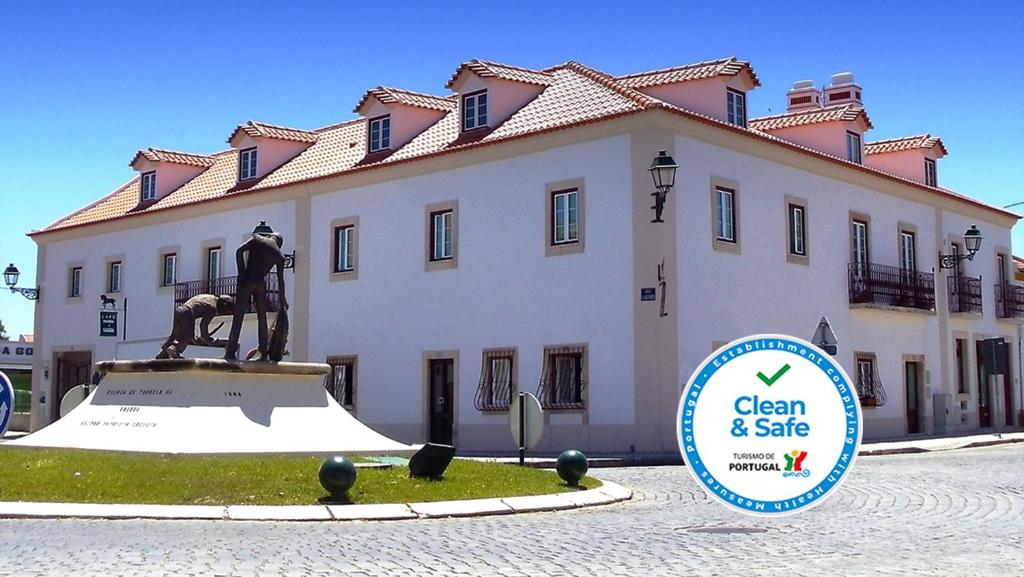 una estatua delante de un edificio con un cartel delante en Casa do Largo - Golegã - Turismo de Habitação, en Golegã