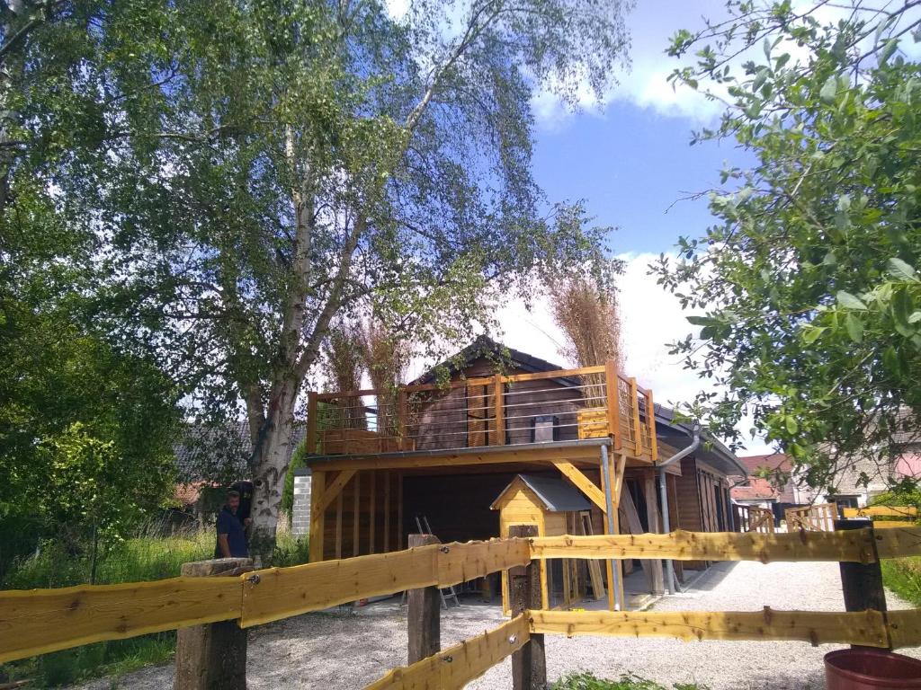 a tree house with a deck on top of it at Le Carport in Hasnon