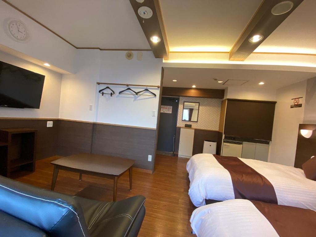 a hotel room with two beds and a flat screen tv at Sejour Fujita in Hiroshima