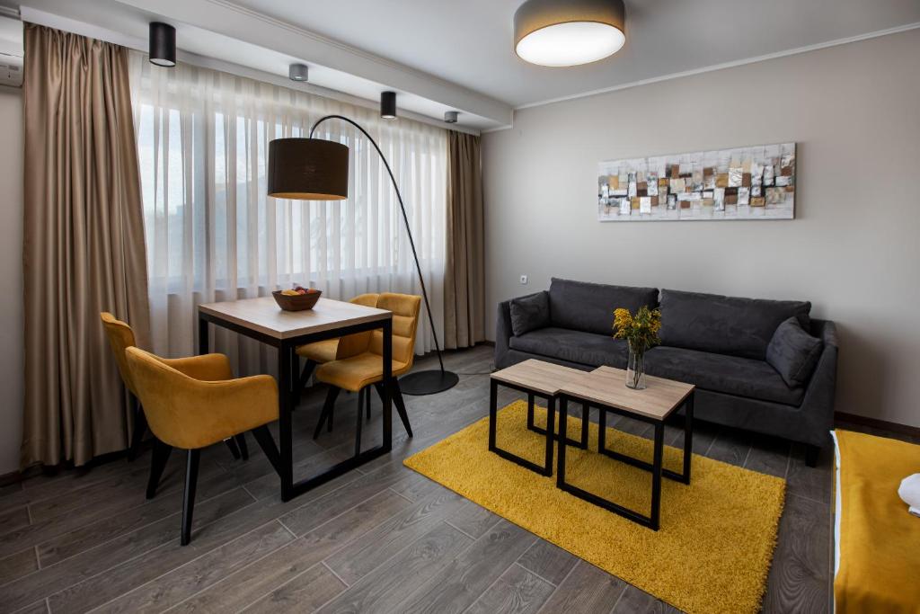 uma sala de estar com um sofá, uma mesa e cadeiras em Annona Apartments em Bečej