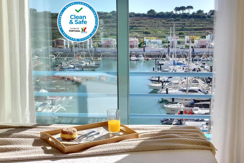 a tray of food and a glass of orange juice on a bed at Marina Ocean Residence in Albufeira