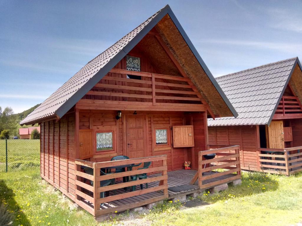 a log cabin with a porch and a deck at Wakacyjne domki in Solina