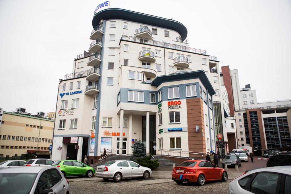 un edificio blanco alto con coches estacionados frente a él en Apartamenty Centrum, en Białystok