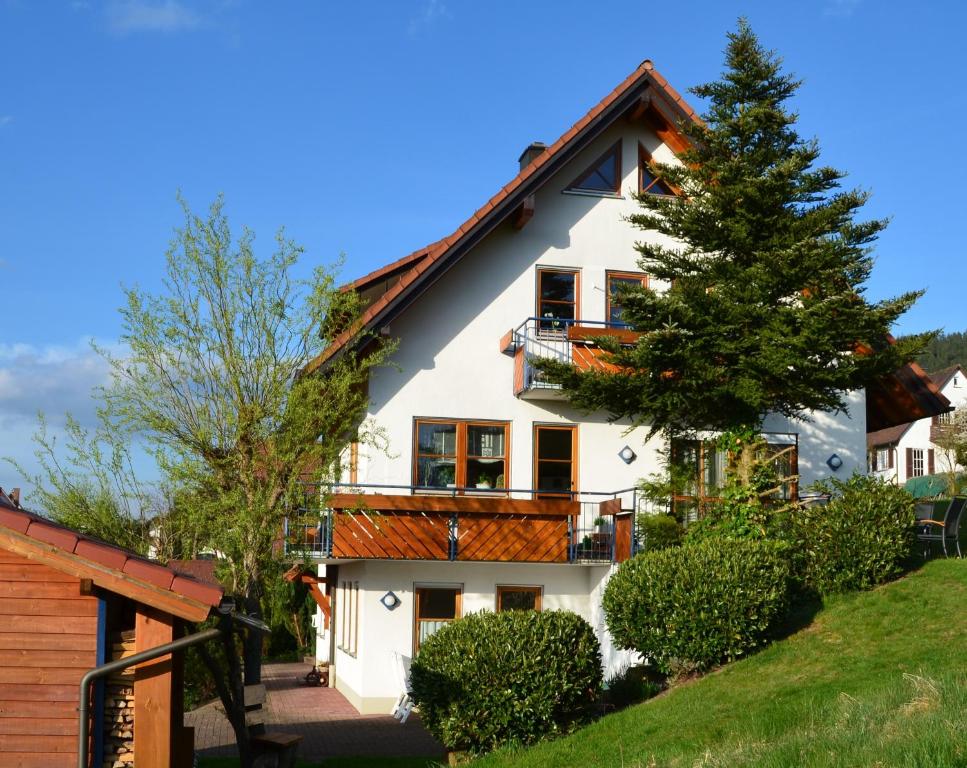 ein weißes Haus mit einem Balkon und einem Baum in der Unterkunft Ferienwohnung Fahrner in Baiersbronn