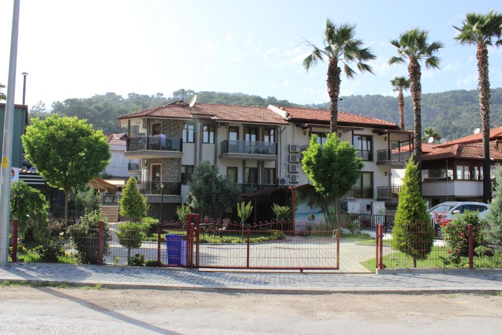 a building with palm trees and a fence at İberia Villas in Ortaca