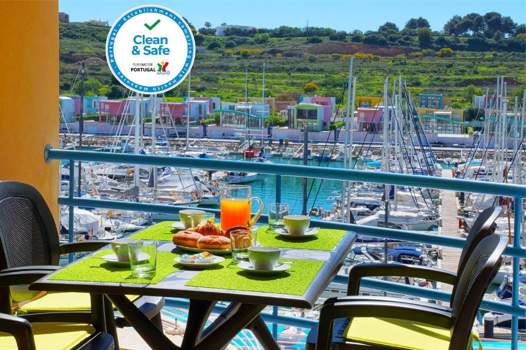 a table with food and drinks on a balcony with a marina at Marina Coast Residence in Albufeira