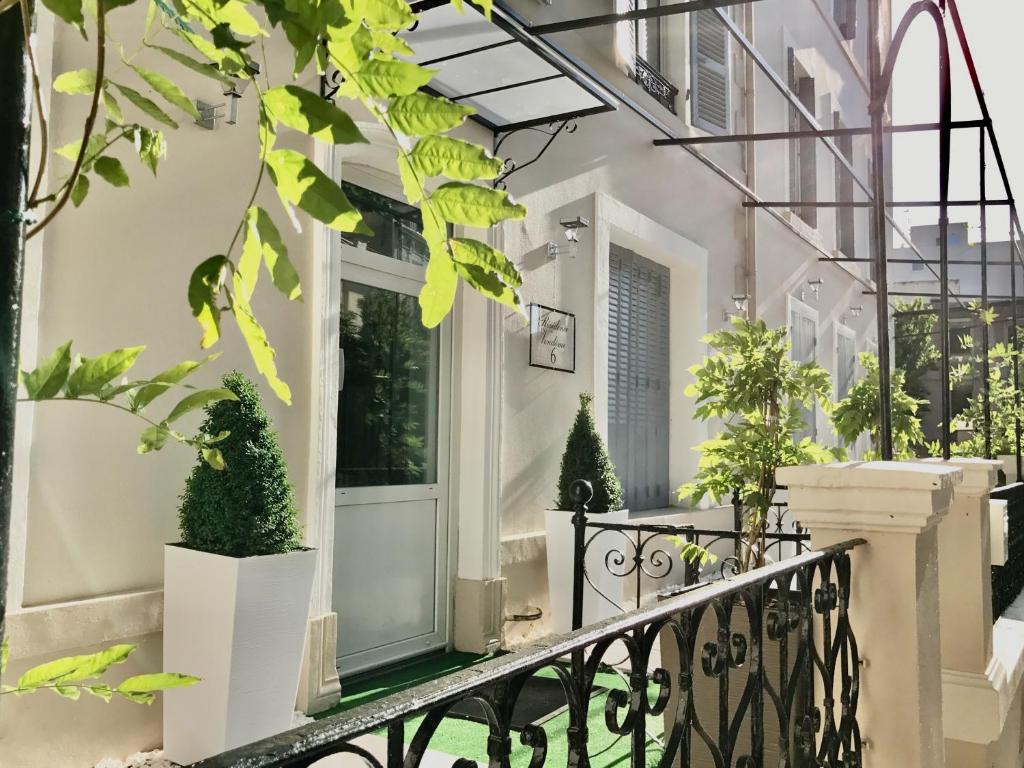 een wit huis met een veranda met potplanten bij Résidence Vendôme in Vichy