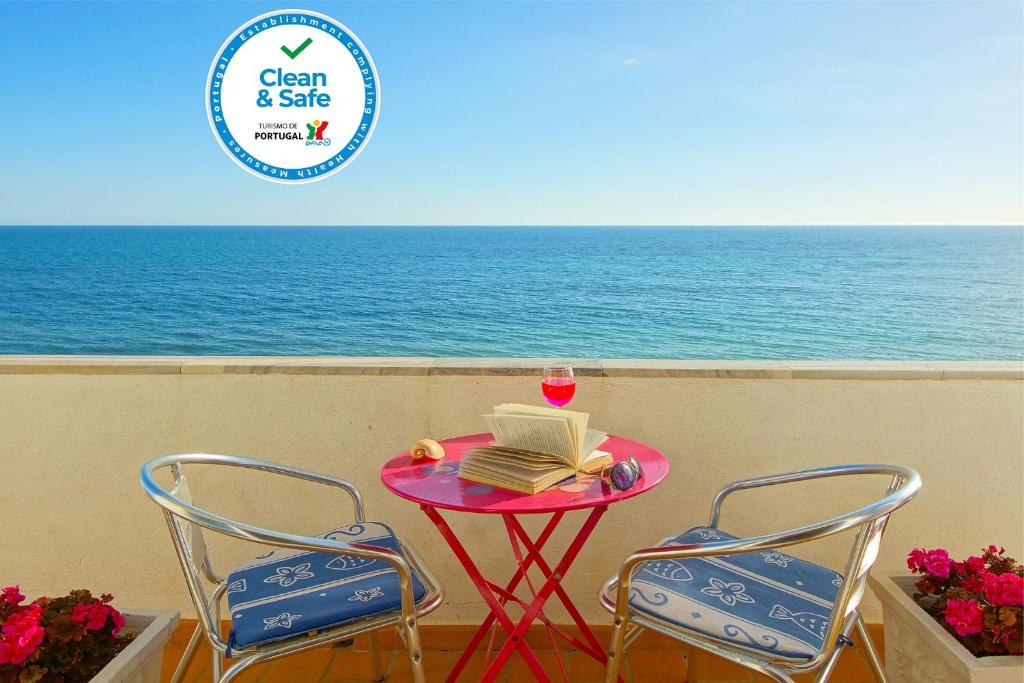 a table with a cake and a glass of wine and two chairs at Inn the Beach Apartments in Albufeira
