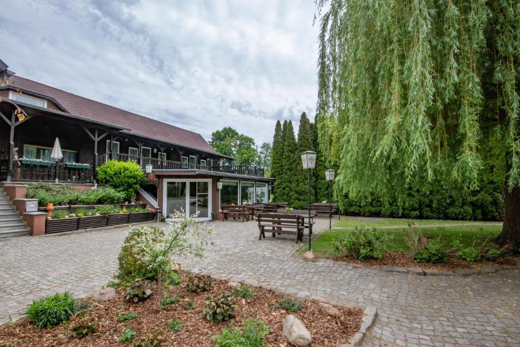 un bâtiment avec une cour dotée de bancs et d'arbres dans l'établissement Storchennest Spreewald, à Vetschau/Spreewald