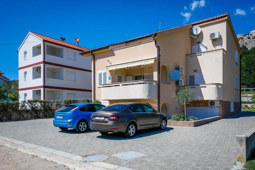 zwei Autos auf einem Parkplatz vor einem Gebäude geparkt in der Unterkunft Apartment Pirun in Baška