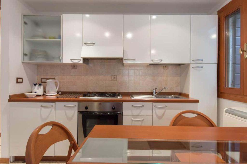 une cuisine avec des placards blancs et une table en bois dans l'établissement Appartamenti Cà d'Oro, à Venise