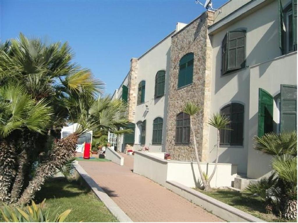 una strada di fronte a un edificio con palme di Albergo Ristorante Lucciola a Santo Stefano al Mare