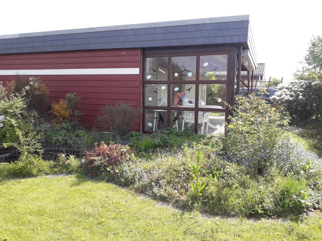 a red building with a window and some flowers at Büsumer blaue Krabbe in Büsum