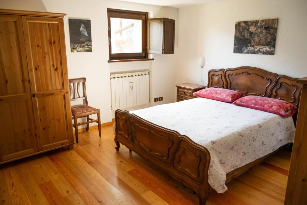 ein Schlafzimmer mit einem großen Holzbett mit rosa Kissen in der Unterkunft Nido delle aquile in Cogne
