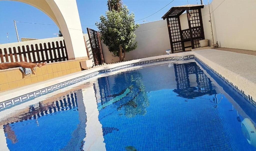 a swimming pool with blue water in front of a house at Flamingo Vila Alicante in San Pedro del Pinatar