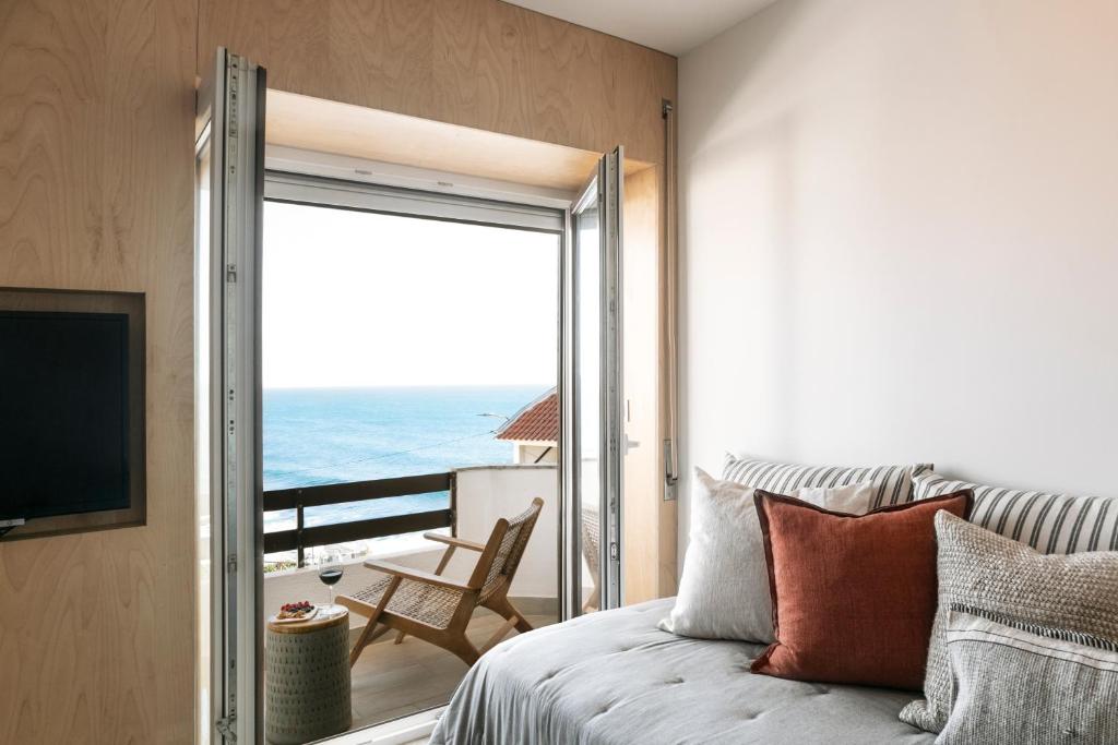 a bedroom with a bed and a view of the ocean at Mare Cheia: Beach and Surf Apartment 2 in Consolação