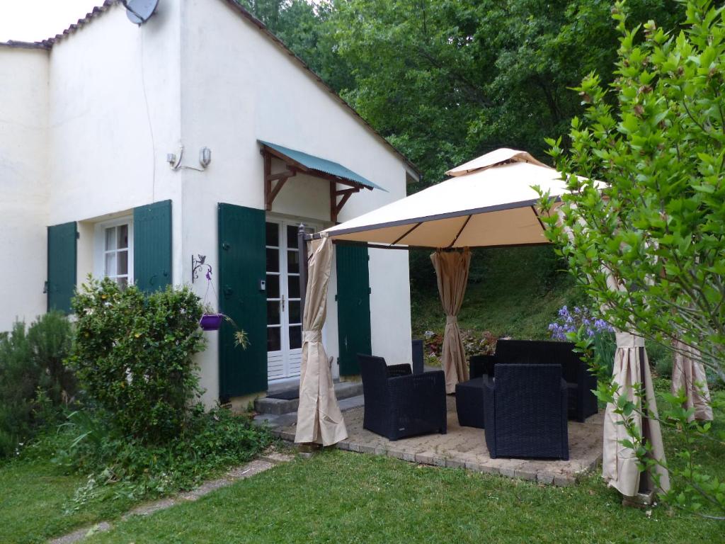 una sombrilla y sillas frente a una casa en Les volets verts, en Lamothe-Montravel