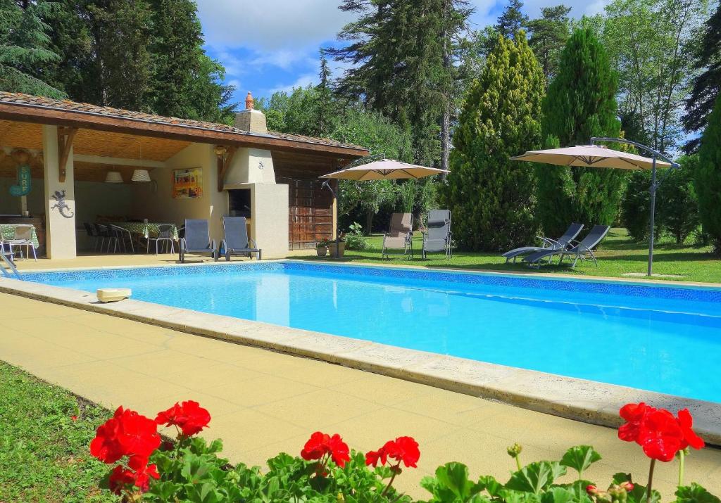 una piscina con flores rojas frente a una casa en Domaine de Pouroutounat, en Mirepoix