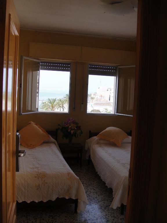 dwa łóżka w pokoju z dwoma oknami w obiekcie HOSTAL COSTA SOL w mieście Castell de Ferro