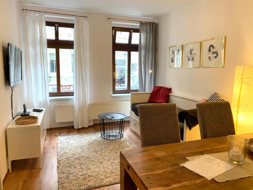 uma sala de estar com uma mesa e cadeiras e um sofá em Hinterhaus Apartment No4 em Leipzig