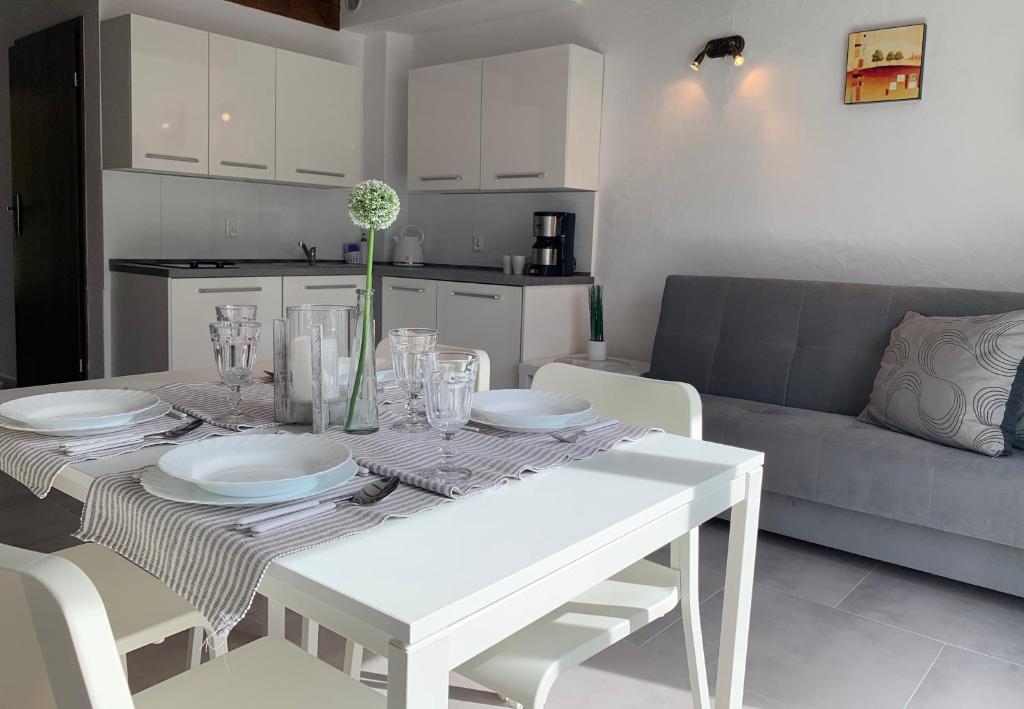 a white dining room table with plates and glasses on it at Domki Magnolia in Dźwirzyno