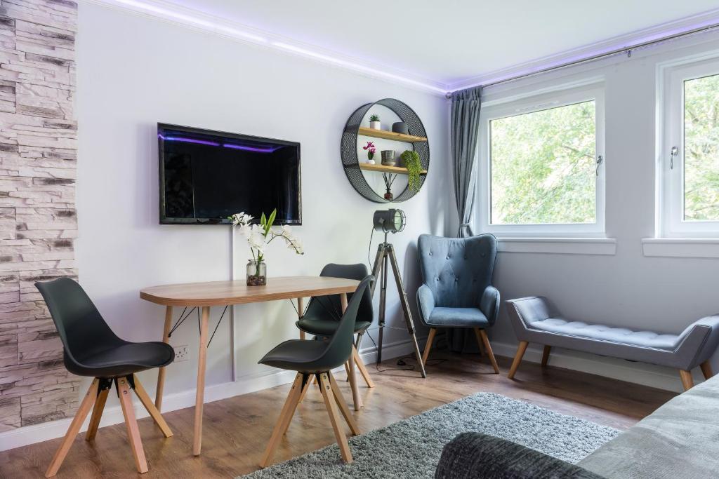 a living room with a table and chairs and a tv at City Centre Stylish Apartment With Free Parking in Edinburgh
