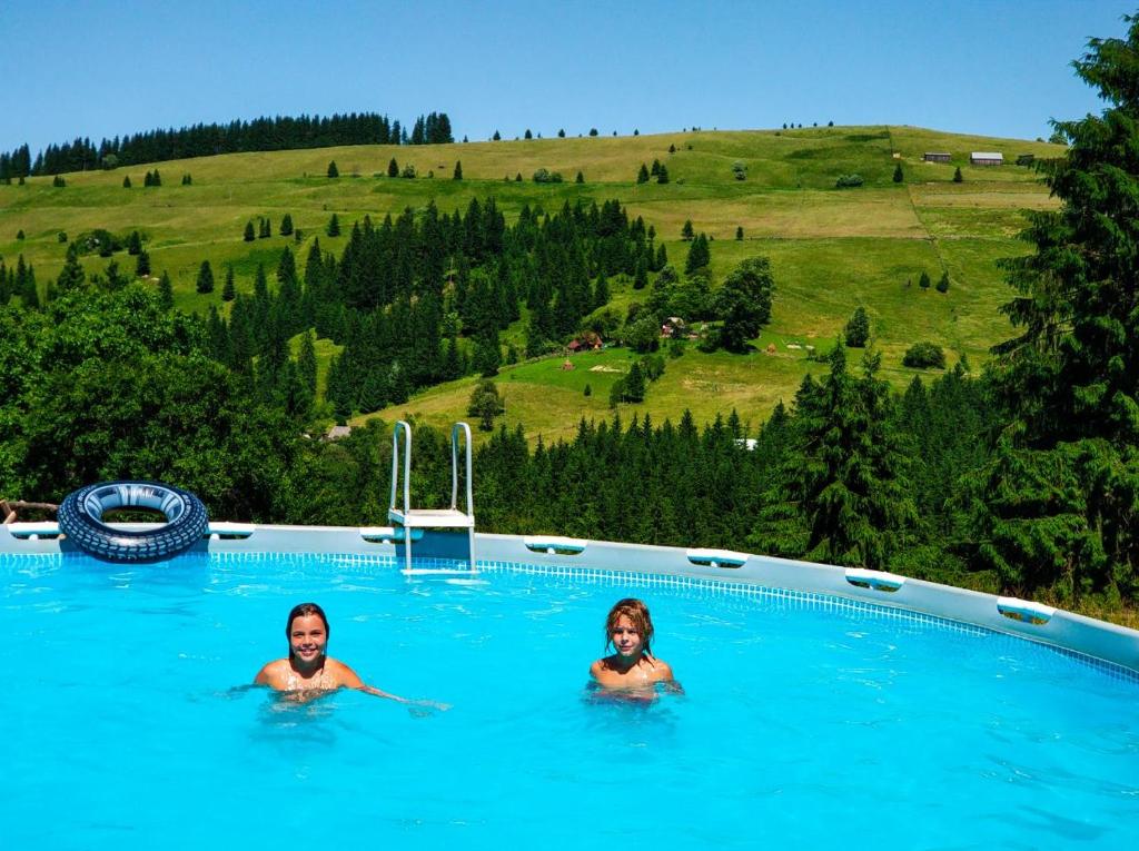 zwei Personen in einem Schwimmbad mit einem Hügel im Hintergrund in der Unterkunft Camping Nad Karpatamy SPA in Hrobyshche
