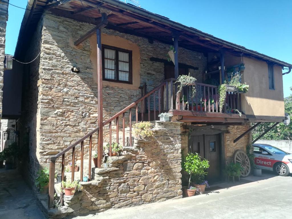 uma casa de pedra com uma escada e uma varanda em Las 3 Negrillas em Toral de Merayo