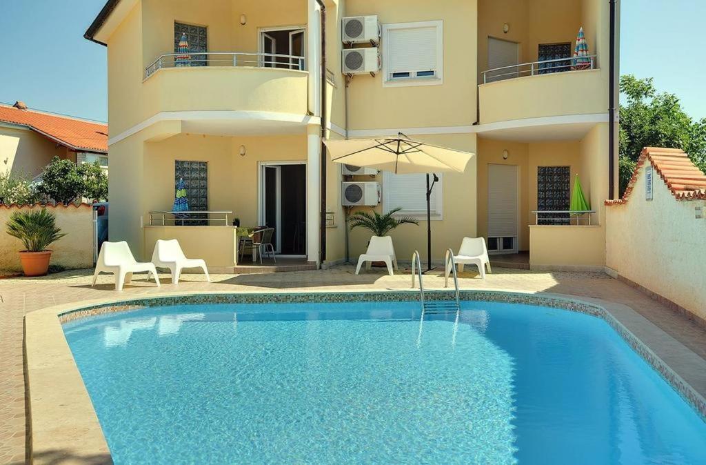une villa avec une piscine en face d'une maison dans l'établissement Apartmani STRIGO, à Medulin