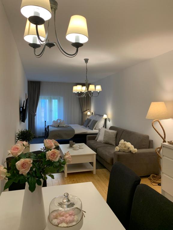 a living room with a couch and a table with flowers at Wise Owl Apartments in Banská Štiavnica