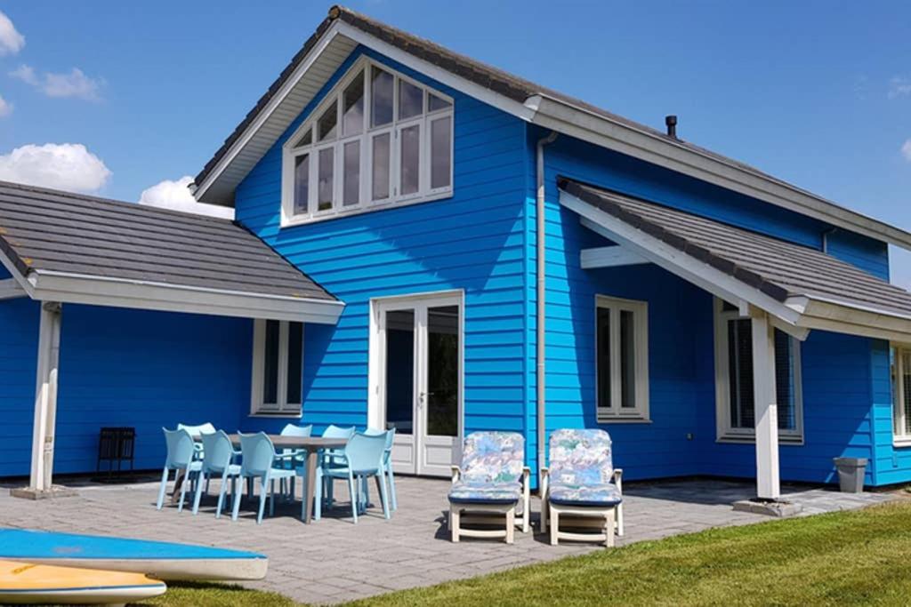 uma casa azul com uma mesa e cadeiras em The Blue House - Luxurious Waterfront Villa Zeewolde em Zeewolde