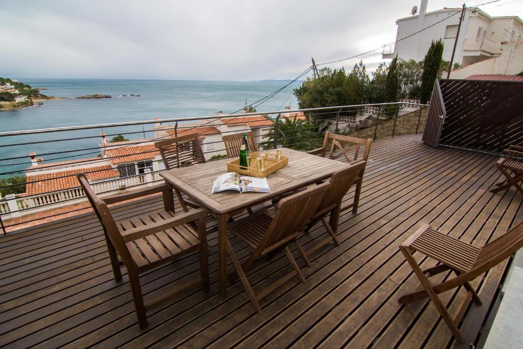 una mesa de madera y sillas en una terraza con vistas al océano en Agi Rodas Apartments, en Roses