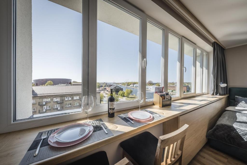 ein Esszimmer mit großen Fenstern sowie einem Tisch und Stühlen in der Unterkunft Best View In Apartment in Liepāja