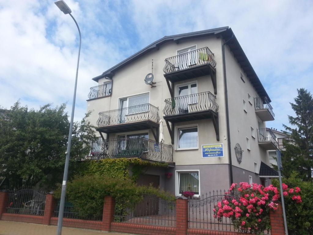 a tall white building with balconies and flowers at Wędrowiec in Karwia
