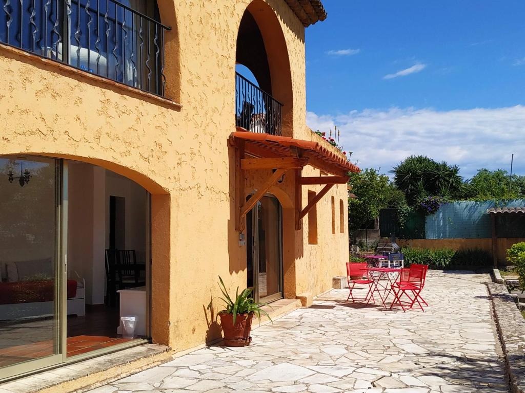 un patio con sillas rojas y un balcón en un edificio en Rez-de-villa Mougins, en Mougins