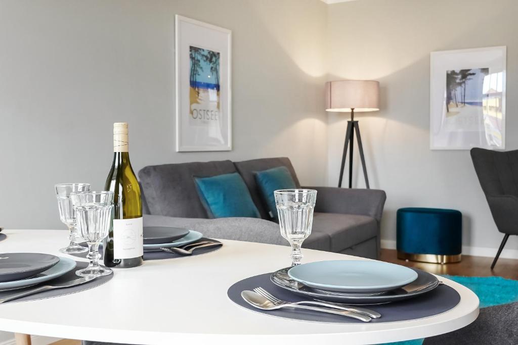 a white table with a bottle of wine and glasses at Strand11 Hochwertige Ferienwohnungen Ahlbeck in Ahlbeck