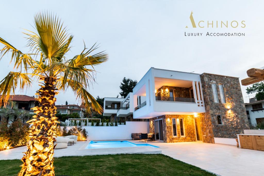 a villa with a palm tree in front of it at Achinos Luxury Accomodation- Pefkochori Chalkidiki in Pefkohori