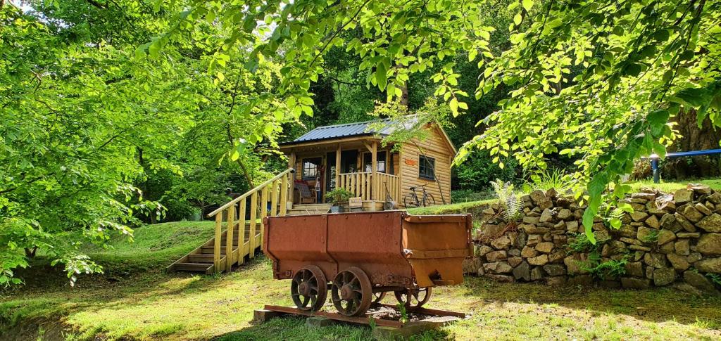 a small wooden cabin with a cart in front of it at Miners log cabin in Blaina