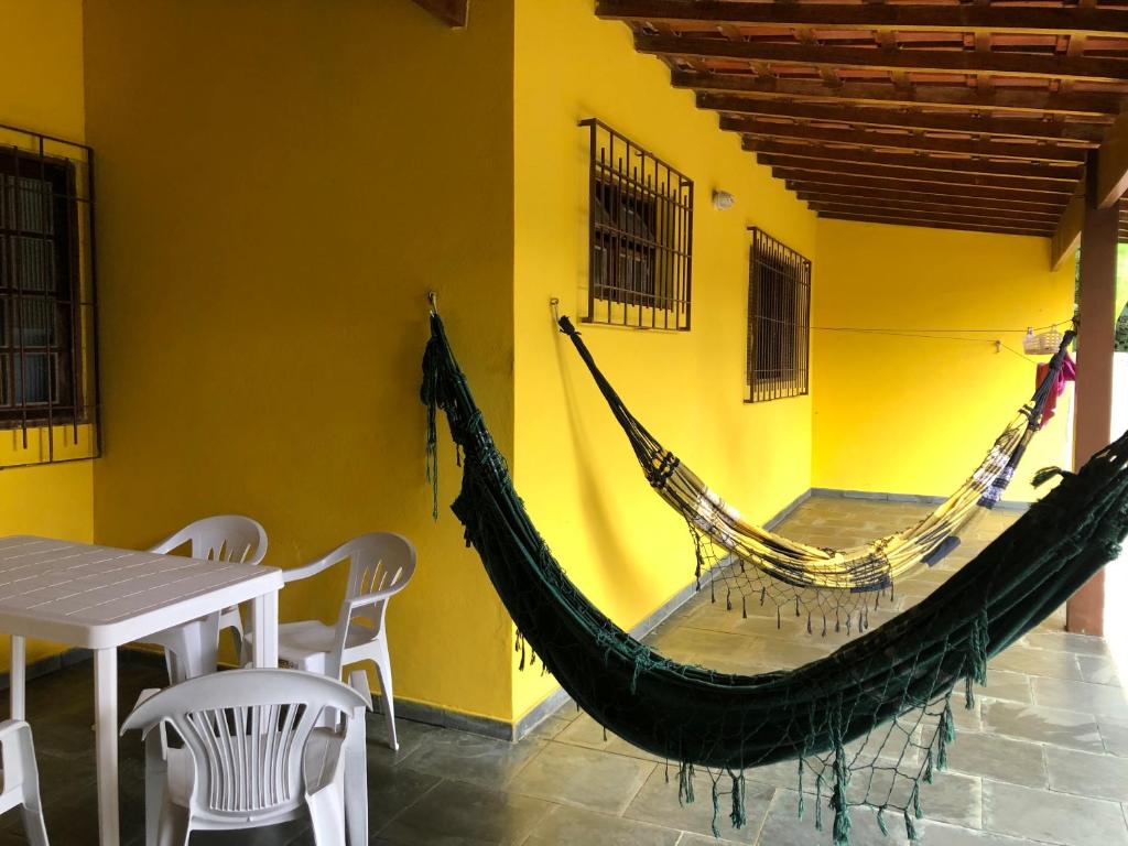 a hammock in a room with a table and chairs at Casa em frente à praia Boracéia in Boracéia