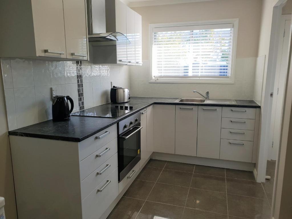 a kitchen with white cabinets and a black counter top at Rose Apartments Unit 1 Central Rotorua-Accommodation&Spa in Rotorua