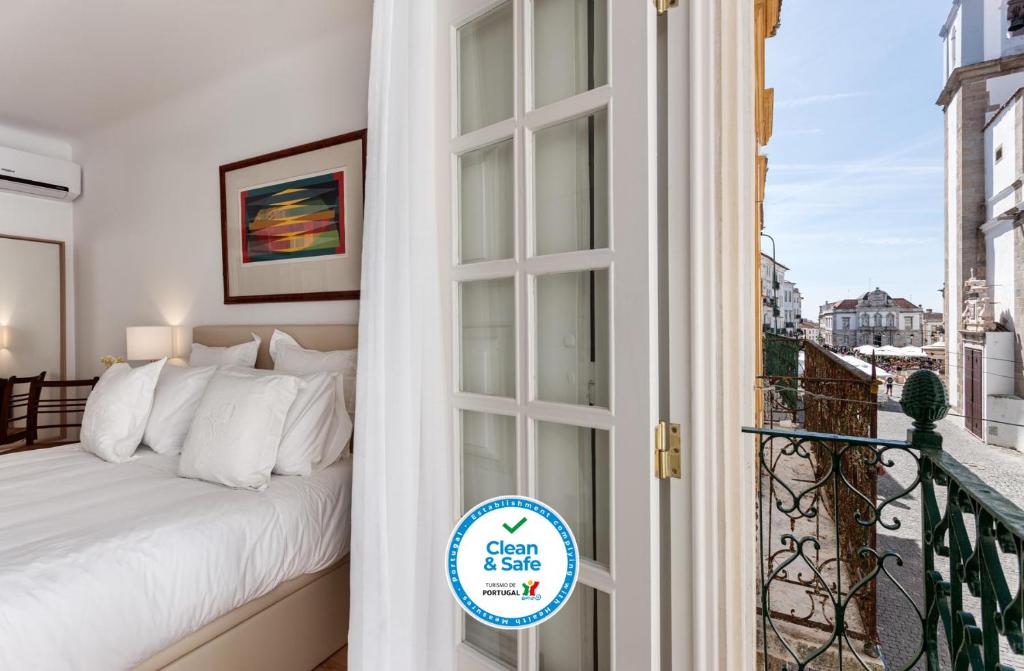 a bedroom with a bed and a balcony with a window at Casa das Arcadas, com free garagem - Praça de Giraldo in Évora