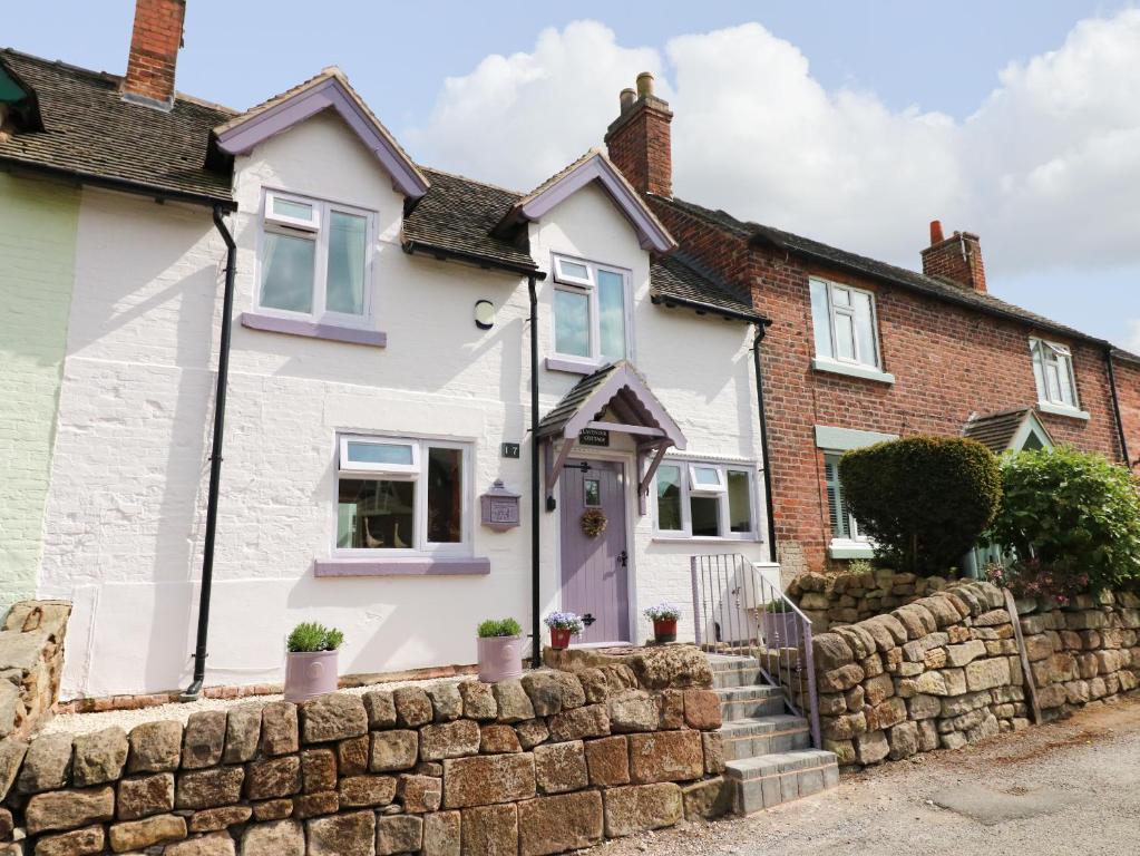 a white house with a stone wall at Lavender Cottage in Ilkeston