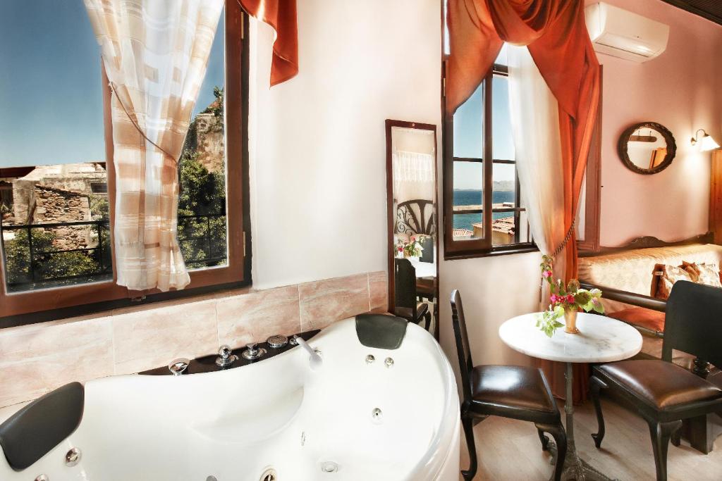 baño con bañera, mesa y ventanas en Archontiko Evgenia Studios & Suites Old Town Chania, en La Canea