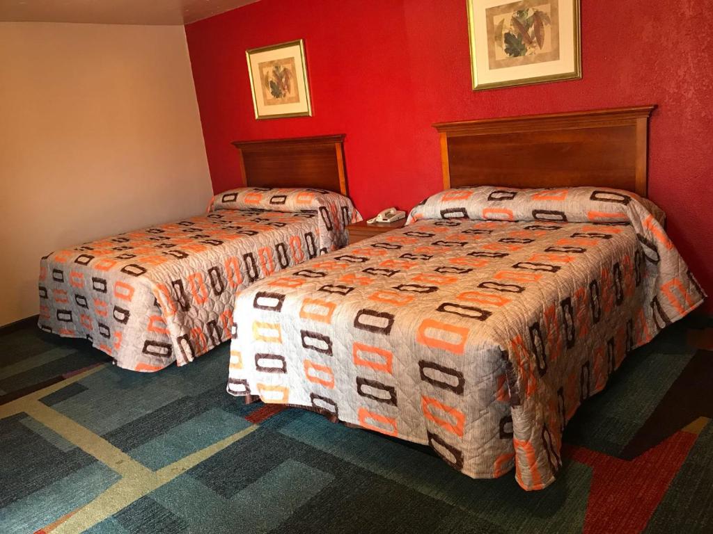 duas camas num quarto de hotel com paredes vermelhas em Budget Inn El Reno em El Reno